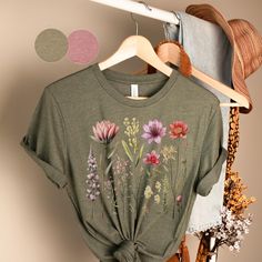 Wildflower Meadow T-Shirt | Bella and Canvas | Heather Olive & Heather Mauve Product Description: Celebrate the beauty of nature with our Wildflower Meadow T-Shirt, available in the captivating colors of Heather Olive and Heather Mauve. This Bella and Canvas t-shirt features a delightful front design that showcases a meadow bursting with multiple wildflowers in a soft and enchanting pink color scheme. Key Features: Premium Quality Comfort: Made with Bella and Canvas for exceptional softness, comfort, and durability. Nature-Inspired Design: The wildflower meadow design captures the vibrant and gentle beauty of the great outdoors. Why Choose Our Wildflower Meadow T-Shirt: 🌸 Natural Elegance: The wildflowers in their various shades of pink are a celebration of nature's artistry. 🎨 Soft and Botanical Short Sleeve Tops With Relaxed Fit, Botanical Green Tops With Plant Print, Green Tops With Plant Print For Spring, Green Cottagecore Top For Spring, Summer Botanical Tops With Floral Embroidery, Summer Botanical Floral Embroidery Tops, Botanical Relaxed Fit Top For Spring, Relaxed Fit Botanical Tops For Spring, Botanical Short Sleeve Summer Tops