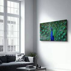 a living room with a couch, coffee table and large window that has a painting of a peacock on it