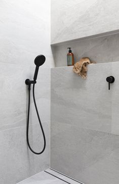 a shower head and hand held shower faucet in a white tiled bathroom with black fixtures