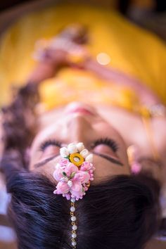 a woman laying on top of a bed wearing a head piece with flowers in it