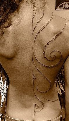 the back of a woman's body with tattoos on it