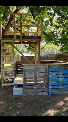 a wooden structure sitting in the middle of a yard next to a tree and fence