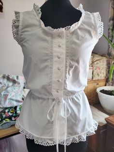 Vintage Style Chemise/Summer Top -- lacy, light, very feminine. This would look great with a flowing skirt, jeans, Capri. The top is made from cotton broadcloth or muslin, either white or ecru/ivory. Vintage stitching on both front and back and will vary by chemise. Ribbon-tied waist to gather to your specific needs. Eyelet lace surrounds the neck, arms, and hemline. Eight buttons and the buttons are vintage and may be slightly off as far as a slight variance in size or variance in minimal color Skirt Jeans, Minimal Color, Couture Vintage, Flowing Skirt, Eyelet Lace, Make Color, Mode Vintage, Summer Top, Vintage Stil