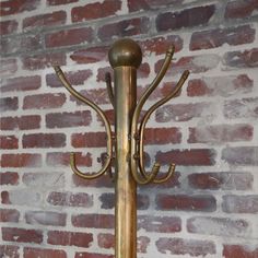 a metal coat rack with three hooks on it and a brick wall in the background