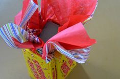 a box with tissue paper wrapped around it and some candy on the inside, sitting on a table