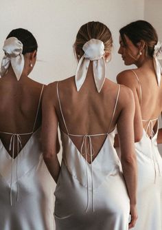 three women in white dresses with bows on their back