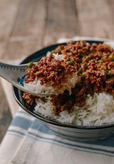 a bowl filled with rice and ground beef on top of a blue and white checkered table cloth