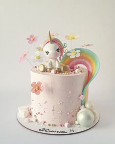 a pink cake decorated with flowers and a unicorn figurine sitting on top of it