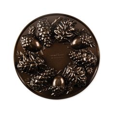 a decorative metal plate with pine cones and bells on it's rim, set against a white background