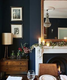 the dining room table is set for dinner with candles and flowers in front of the fireplace