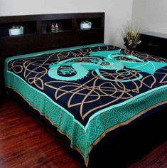 a bed with a blue and black bedspread on top of wooden flooring