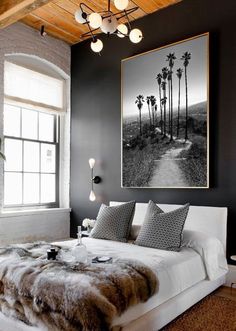 a bedroom with black walls, white bedding and palm trees hanging on the wall