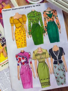 the paper doll is next to some sewing patterns for dresses and blouses on a table