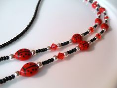 Length: Apprx 28" end to end Adorable Red and Black Ladybug Eyeglass Chain Eyeglass chains make lovely handmade gifts for those difficult-to-buy-for people in your life: family, friends, coworkers, etc. Composition: Czech glass ladybug beads and seed beads   Swarovski crystal bicones in red  Silverplated beads and components - crimps, covers, split rings and wire guardians for a professional finished appearance Silver corrugated bead with black elastic cord eyeglass ends Professional, high strength & flexible beading cable - (multistrand stainless steel wire w/ nylon coating for a soft silky feel) This delightful artisan-handcrafted eyeglass chain will arrive in a pretty cotton-lined jewelry box - perfect for gift giving. Special Requests: I am happy to customize a piece for you to suit yo Red Glass Glasses Chains As A Gift, Red Glass Glasses Chains For Gift, Adjustable Red Glass Glasses Chains, Red Glass Jewelry With Adjustable Chain, Black Ladybug, Eyeglass Chains, Eyeglasses Chain, Sunglasses Chain, Black Eyeglasses