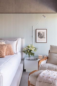 a white couch sitting in a living room next to a chair and table with flowers on it