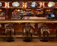 the bar is decorated with wooden carvings and decorative mirrors, along with leather stools