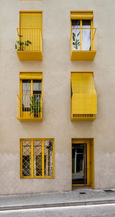 an apartment building with balconies and yellow shutters