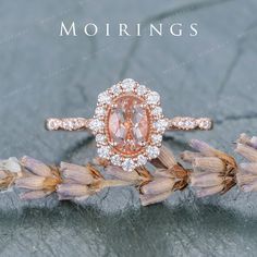 a ring with an oval shaped peach diamond surrounded by smaller round diamonds on top of it