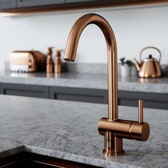 a kitchen with marble counter tops and copper faucet