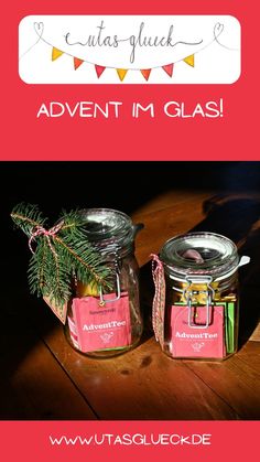 two glass jars filled with candy sitting on top of a wooden table next to a pine tree