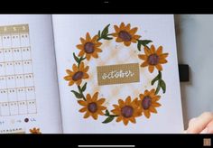 an open planner book with sunflowers and the word october written in cursive writing