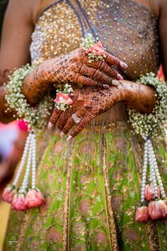 the bride's hands are adorned with flowers and pearls, while she wears her wedding jewelry