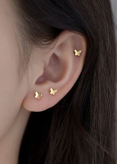 a woman's ear with two small gold butterflies on the back of her ear