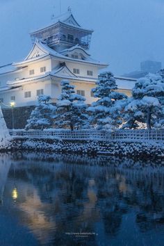 a large white building sitting on top of a snow covered hill next to a body of water