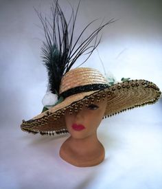 This festively fun hat is a true attention getter.   This is made on a straw hat.  Splashes of white, black and green adorn the hat- . There is a tall black spray, off white roses, ostrich feathers.  The brim is embellished with glass beading, and the hat band is black with black beading.   Our sweater crew love to display their talents on things other than sweaters, this is just one example.   This is an extravagant fun hat.   You can show this off at any event, or just out for coffee. measurem Summer High Crown Hats For Country Events, High Crown Hats For Summer Country Events, Summer Country Events High Crown Hats, Vintage Mini Hats For Spring Festivals, Spring Festival Costume Hat With Short Brim, Bohemian Costume Hats And Headpieces For Spring Party, Bohemian Spring Party Costume Hats And Headpieces, Spring Festival Vintage Mini Hats, Straw Brimmed Sun Hat For Party