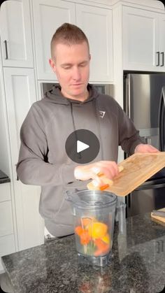 a man standing in front of a kitchen counter with oranges on the cutting board