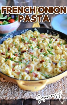 a skillet filled with macaroni and cheese on top of a wooden table