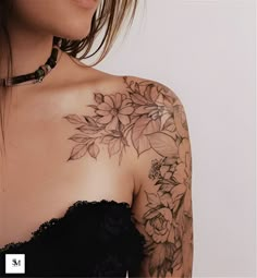 a woman wearing a black dress with flowers on her chest and arm tattoo design in front of her shoulder