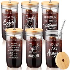 four glass jars with wooden lids and labels on them, each containing the same message