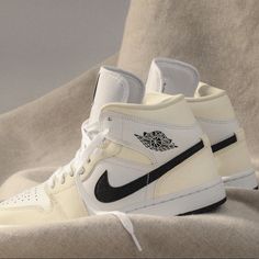 a pair of white and black sneakers sitting on top of a bed covered in sheets