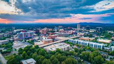 an aerial view of the city of greenville, tennessee at sunset with clouds in the sky