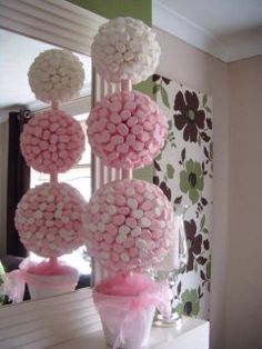 pink and white decorations are hanging from the ceiling in front of a mirror on a dresser