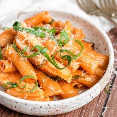 a white bowl filled with pasta covered in sauce and parmesan cheese on top