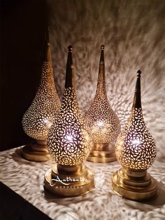 three decorative vases sitting on top of a table next to each other with lights in them