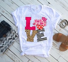 a t - shirt with the letter l on it next to sandals and flip flops