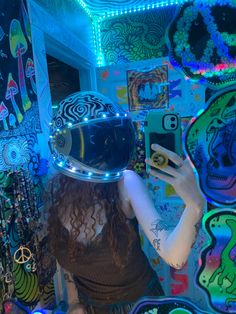 a woman with a helmet on taking a selfie in front of a wall full of colorful images