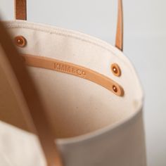 The Natural Canvas tote is a canvas and leather tote handmade in the KMM & Co. studio in Atlanta. Each one is meticulously crafted from heavyweight canvas (which is durable enough to stand up on its own) and gorgeous full-grain leather. Natural Canvas is an undyed cotton canvas, and the natural fibers have some subtle color variation that makes the canvas look slightly speckled. The Natural Canvas tote comes standard with Russet handles. Bucket Canvas Bag With Leather Trim, Large Canvas Bag With Leather Handles, Modern Bucket Canvas Bag With Canvas Lining, Modern Canvas Bucket Bag With Canvas Lining, Classic Canvas Bag With Leather Handles, Cotton Canvas Bucket Bag With Leather Handles, Modern Everyday Canvas Bag With Canvas Lining, Classic Canvas Bag With Leather Handles For Everyday, Large Beige Canvas Bag