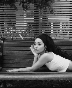 black and white photograph of a woman laying on a bench with her hand under her chin