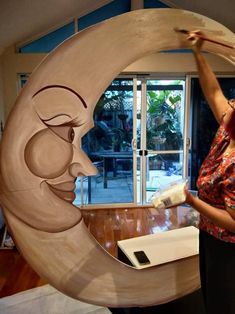 a woman standing in front of a wooden moon