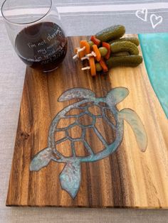 a wooden cutting board topped with vegetables and a turtle cut in half next to a glass of wine