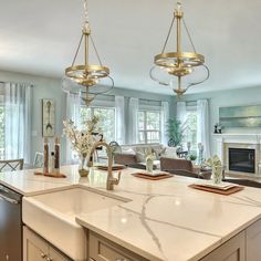 a large kitchen with an island in the middle and two chandeliers hanging from the ceiling