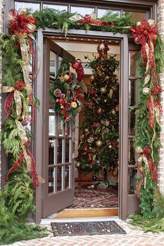 a decorated christmas tree is seen through an open door with holiday decorations on the outside