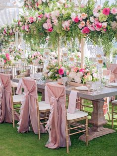 the tables are set up with pink and white flowers hanging from the ceiling above them