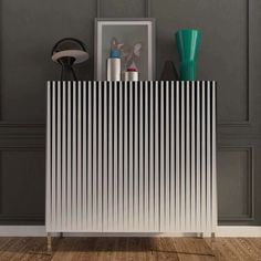 a white radiator sitting on top of a wooden floor next to a vase