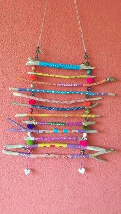 a wall hanging made out of toothbrushes on a pink wall with beads and tassels