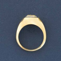 a yellow gold ring sitting on top of a blue surface with the center stone missing